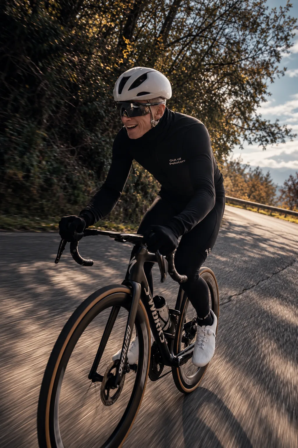 Rider in the black Pro Team Thermal Jacket descending a tree-lined road in low autumn light